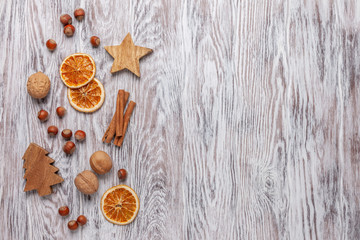 Сhristmas border made of wooden christmas ornaments, dried oranges, nuts and cinnamon sticks on wooden background. Flt lay, top view