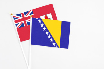 Bosnia Herzegovina and Bermuda stick flags on white background. High quality fabric, miniature national flag. Peaceful global concept.White floor for copy space.