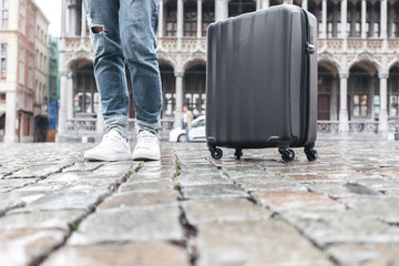 Woman tourist goes with a suitcase at the Grand Place in Brussels, Belgium
