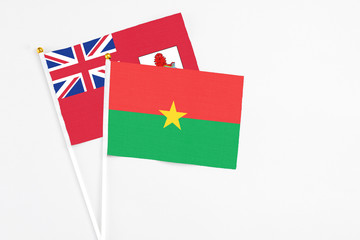 Burkina Faso and Bermuda stick flags on white background. High quality fabric, miniature national flag. Peaceful global concept.White floor for copy space.