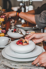 close up of a hand with sppon over a porcelaine plate of fruit salade
