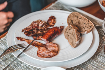 Close up of sausage and bacon in homade brunch with food in unique porcelaine plate