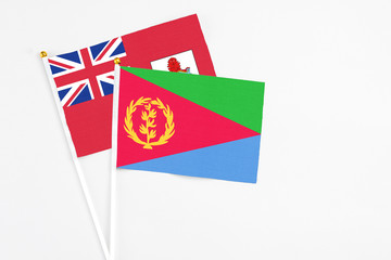 Eritrea and Bermuda stick flags on white background. High quality fabric, miniature national flag. Peaceful global concept.White floor for copy space.