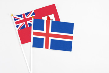 Fototapeta premium Iceland and Bermuda stick flags on white background. High quality fabric, miniature national flag. Peaceful global concept.White floor for copy space.