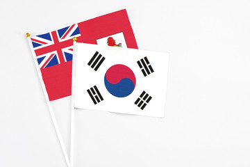South Korea and Bermuda stick flags on white background. High quality fabric, miniature national flag. Peaceful global concept.White floor for copy space.