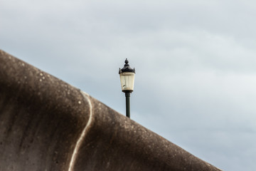 Old street lamp behind railing on lamp post turned off, lantern light at day