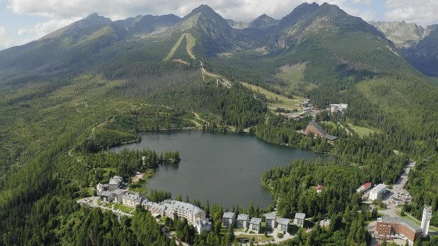 Tilt Up Drone Shot Alpine Lake and Resorts on Mountainside, High Tatras Slovakia