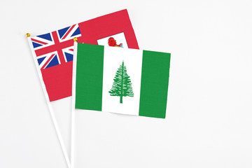 Norfolk Island and Bermuda stick flags on white background. High quality fabric, miniature national flag. Peaceful global concept.White floor for copy space.