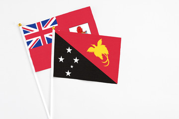 Papua New Guinea and Bermuda stick flags on white background. High quality fabric, miniature national flag. Peaceful global concept.White floor for copy space.