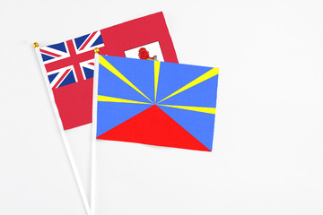 Reunion and Bermuda stick flags on white background. High quality fabric, miniature national flag. Peaceful global concept.White floor for copy space.