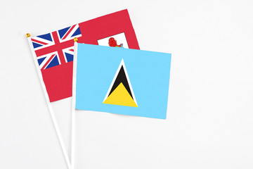 Saint Lucia and Bermuda stick flags on white background. High quality fabric, miniature national flag. Peaceful global concept.White floor for copy space.