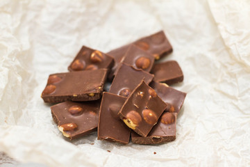 brown chocolate with whole nuts. slices of dark chocolate. broken chocolates on the table. milk sweets. The view from the top. Space for text.