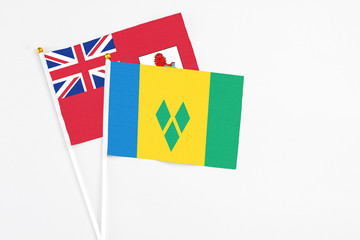 Saint Vincent And The Grenadines and Bermuda stick flags on white background. High quality fabric, miniature national flag. Peaceful global concept.White floor for copy space.