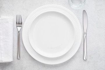 Table setting with white plates, glass, napkin, fork and knife.