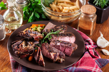 Slices of beef steak served with baked artichoke
