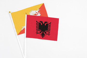 Albania and Bhutan stick flags on white background. High quality fabric, miniature national flag. Peaceful global concept.White floor for copy space.
