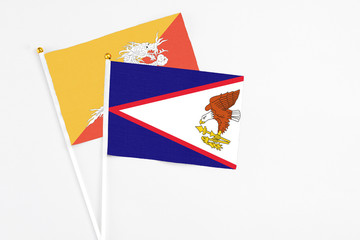 American Samoa and Bhutan stick flags on white background. High quality fabric, miniature national flag. Peaceful global concept.White floor for copy space.