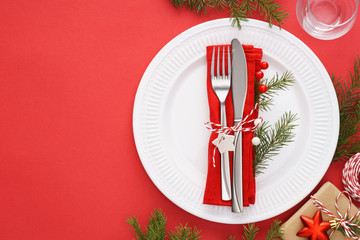 Christmas table setting with white plates, napkin and cutlery.