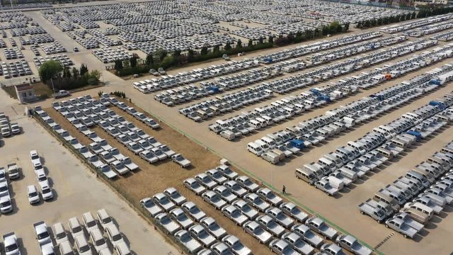 Bird's eye perspective of seemingly endless rows of SUVs and other vehicles on parking lot of car factory in Qingdao, industry and economy China