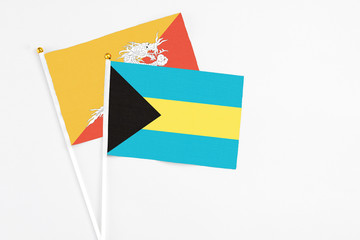 Bahamas and Bhutan stick flags on white background. High quality fabric, miniature national flag. Peaceful global concept.White floor for copy space.