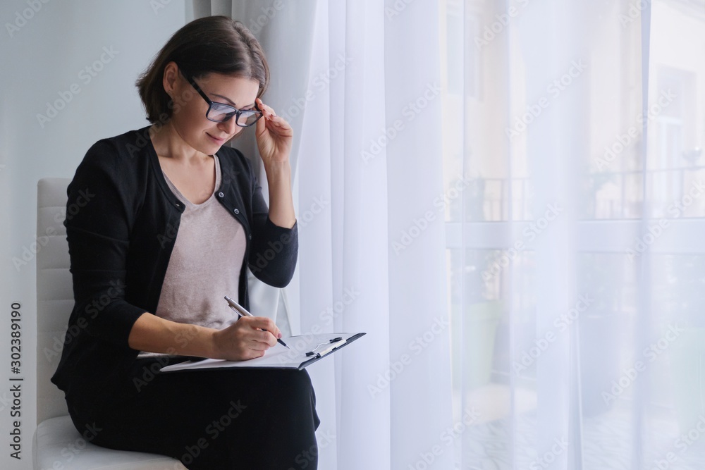 Wall mural Mature business woman writing on business papers