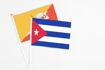 Cuba and Bhutan stick flags on white background. High quality fabric, miniature national flag. Peaceful global concept.White floor for copy space.