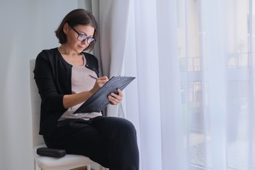 Mature business woman writing on business papers