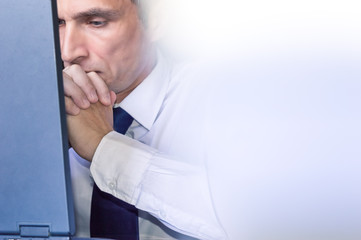 Fototapeta premium View of worried 40s Caucasian businessman using laptop at office.
