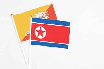 North Korea and Bhutan stick flags on white background. High quality fabric, miniature national flag. Peaceful global concept.White floor for copy space.