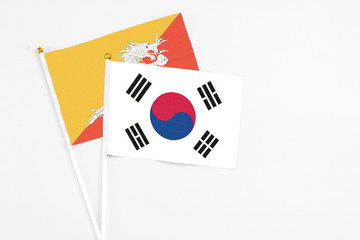 South Korea and Bhutan stick flags on white background. High quality fabric, miniature national flag. Peaceful global concept.White floor for copy space.