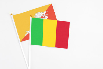 Mali and Bhutan stick flags on white background. High quality fabric, miniature national flag. Peaceful global concept.White floor for copy space.