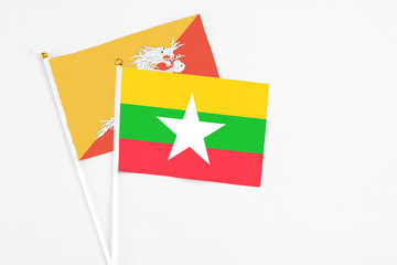 Myanmar and Bhutan stick flags on white background. High quality fabric, miniature national flag. Peaceful global concept.White floor for copy space.