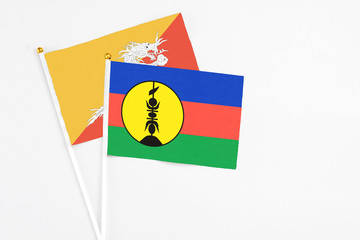 New Caledonia and Bhutan stick flags on white background. High quality fabric, miniature national flag. Peaceful global concept.White floor for copy space.