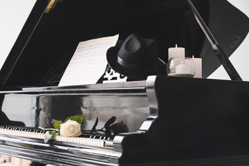 Stylish grand piano with candles and rose flower in room
