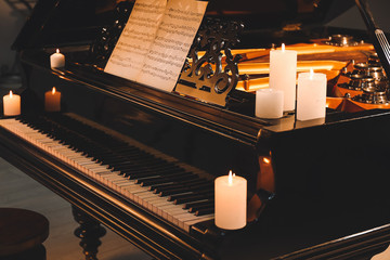 Stylish grand piano with burning candles in evening