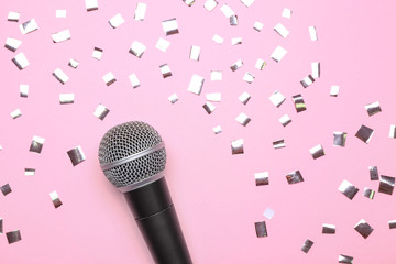 Fototapeta na wymiar Modern microphone and confetti on color background