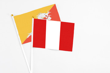 Peru and Bhutan stick flags on white background. High quality fabric, miniature national flag. Peaceful global concept.White floor for copy space.