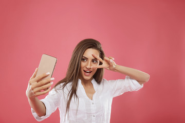 Naklejka premium Close up portrait of young beautiful stylish woman making selfie, using her own smartphone, smiles at camera, photo for social networks.