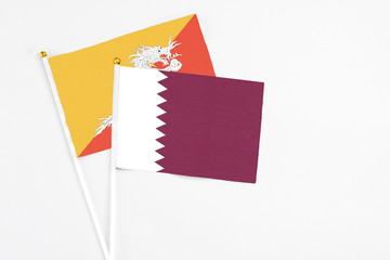 Qatar and Bhutan stick flags on white background. High quality fabric, miniature national flag. Peaceful global concept.White floor for copy space.