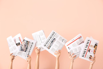 Female hands with newspapers on color background