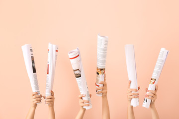 Female hands with newspapers on color background