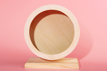 Wooden wheel for a hamster close-up on a pink background