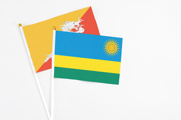 Rwanda and Bhutan stick flags on white background. High quality fabric, miniature national flag. Peaceful global concept.White floor for copy space.