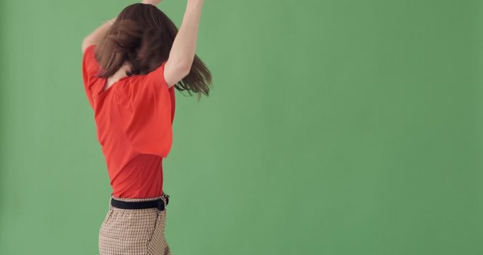 Joyful young woman dancing over green background
