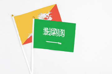 Saudi Arabia and Bhutan stick flags on white background. High quality fabric, miniature national flag. Peaceful global concept.White floor for copy space.