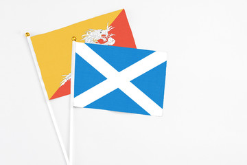 Scotland and Bhutan stick flags on white background. High quality fabric, miniature national flag. Peaceful global concept.White floor for copy space.