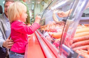 Child in front of the meat counter in a supermarket