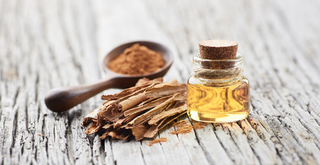 Cinnamon oil with cinnamon bark on wooden background