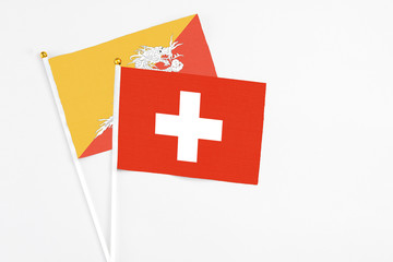 Switzerland and Bhutan stick flags on white background. High quality fabric, miniature national flag. Peaceful global concept.White floor for copy space.