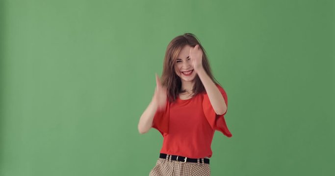 Crazy young woman giving thumbs up gesture and celebrating success over green background